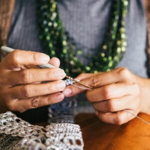 Close-up of a woman creating jewelry using crochet techniques with metal yarn, showcasing skill and creativity.